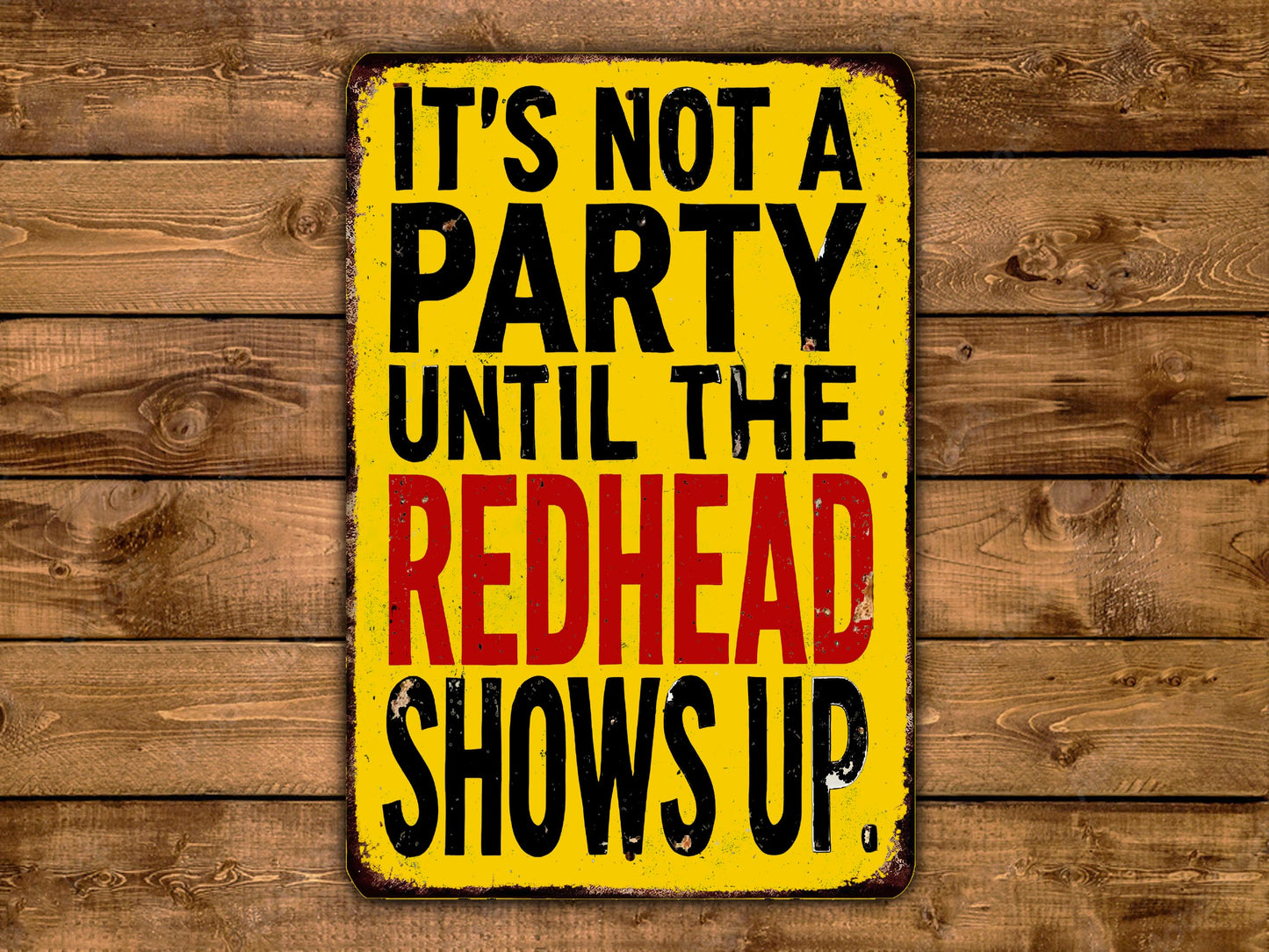 A yellow sign with black text that reads "IT'S NOT A PARTY UNTIL THE REDHEAD SHOWS UP."