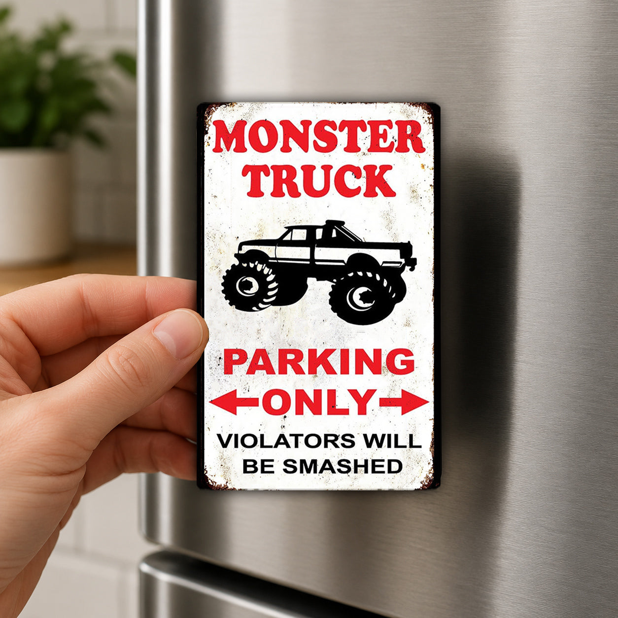 A person's hand is holding a sign that says "MONSTER TRUCK PARKING ONLY VIOLATORS WILL BE SMASHED".