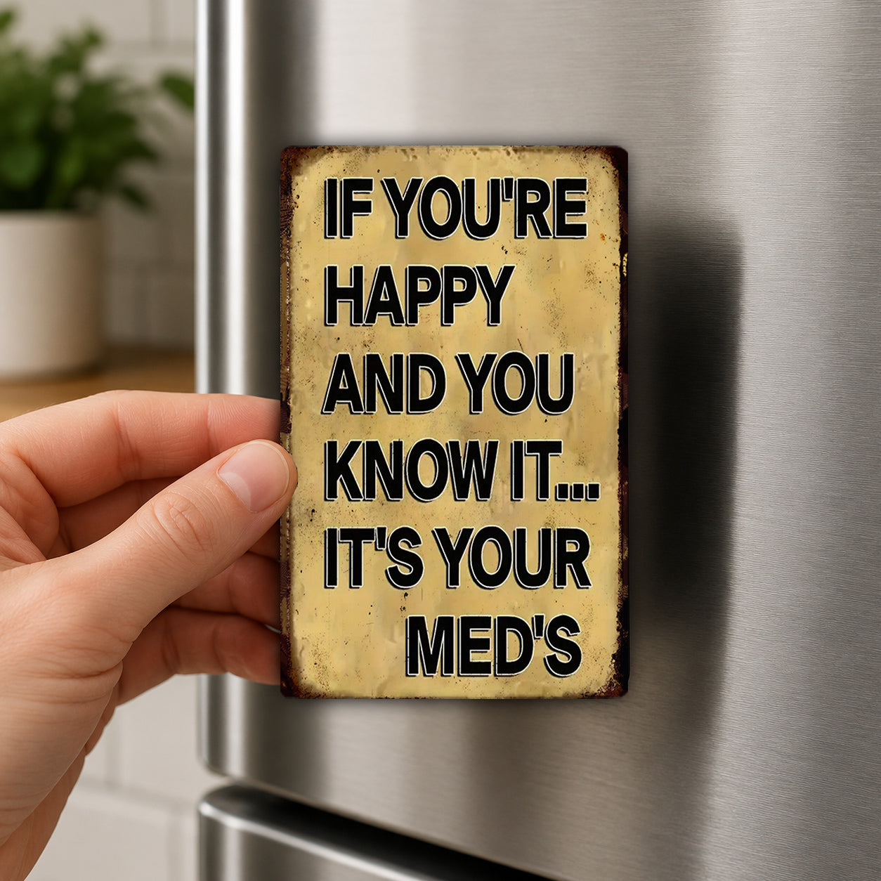 A person's hand holding a small, rectangular sign with text on it, which appears to be a humorous or playful message.