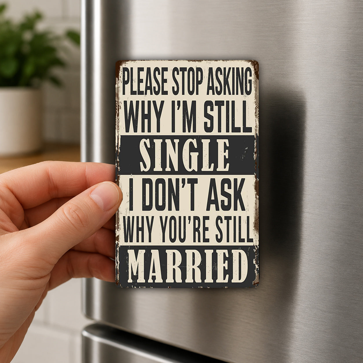 a person's hand holding a small metal sign with text on it, which appears to be a humorous or playful message.