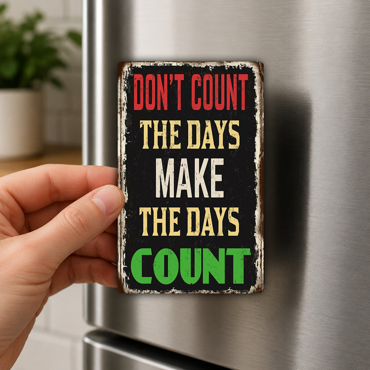 A person's hand holding a sign with the text "DON'T COUNT THE DAYS MAKE THE DAYS COUNTER" on it.