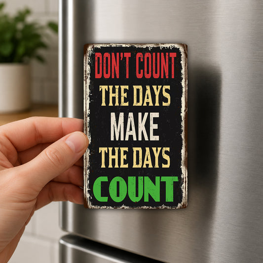 A person's hand holding a sign with the text "DON'T COUNT THE DAYS MAKE THE DAYS COUNTER" on it.