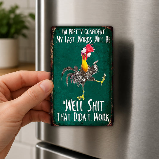 A person's hand is holding a green refrigerator magnet with a cartoon rooster and the text "I'm pretty confident my last words will be 'Well shit that didn't work'".
