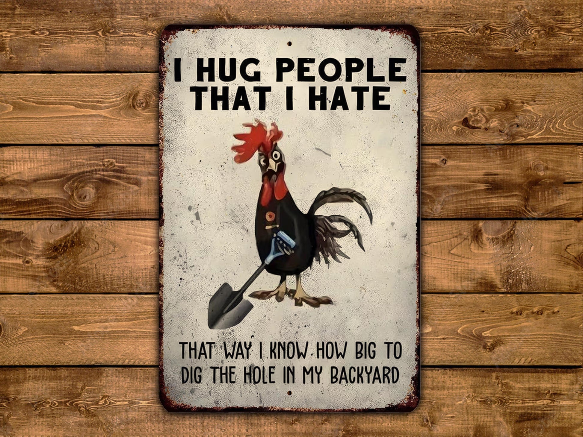 a sign with a rooster holding a shovel, accompanied by the text "I HUG PEOPLE THAT I HATE" and "THAT WAY I KNOW HOW BIG TO DIG THE HOLE IN MY BACKYARD".