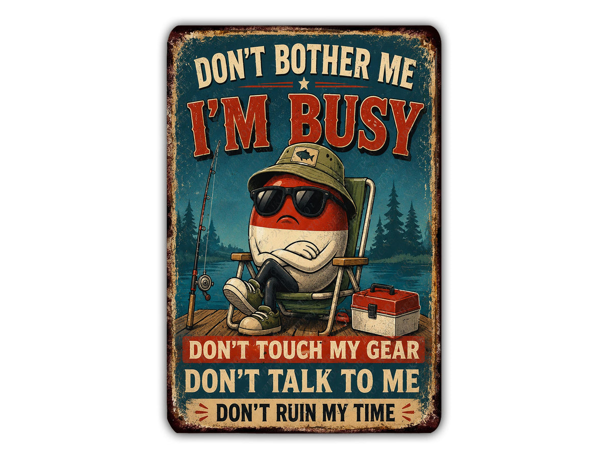a sign with a cartoon character sitting in a chair, wearing sunglasses and holding a fishing rod. The sign has a humorous message that reads "Don't bother me, I'm busy" and "Don't touch my gear, don't talk to me, don't ruin my time".