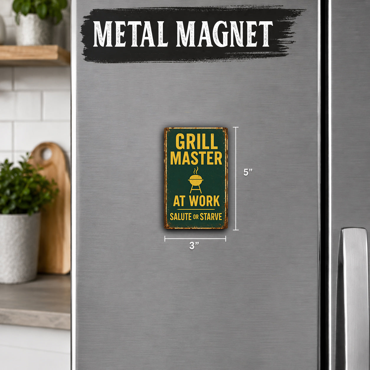 a metallic refrigerator with a small, vintage-style sign that reads "Grill Master at Work Salute or Starve" in the center.