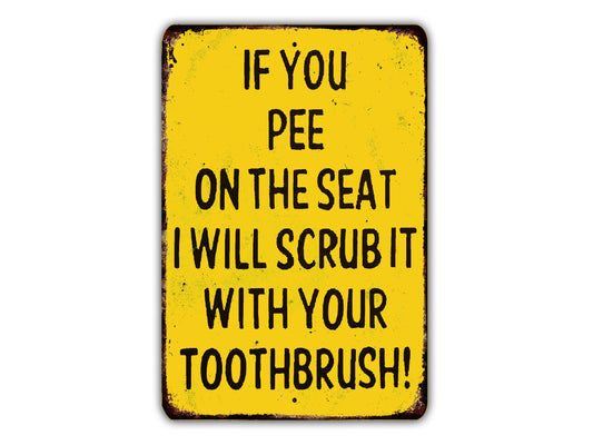 a yellow sign with black text that reads "IF YOU PEE ON THE SEAT I WILL SCRUB IT WITH YOUR TOOTHBRUSH!"