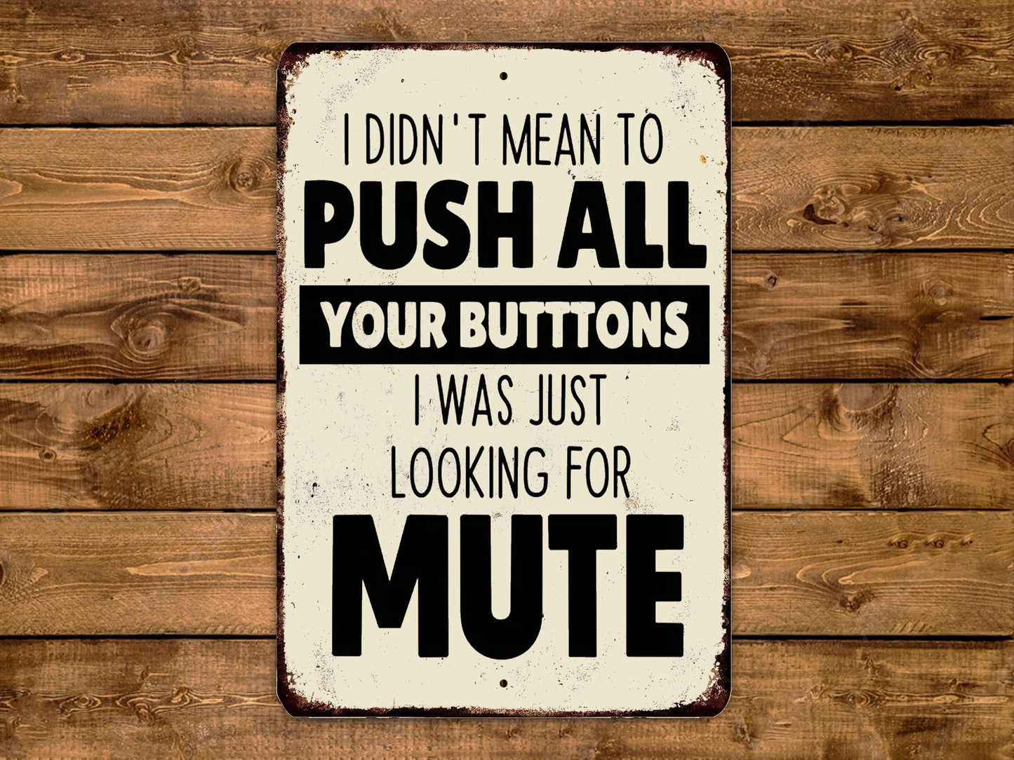 a humorous sign with the text "I DIDN'T MEAN TO PUSH ALL YOUR BUTTONS I WAS JUST LOOKING FOR MUTE" displayed on a wooden background.