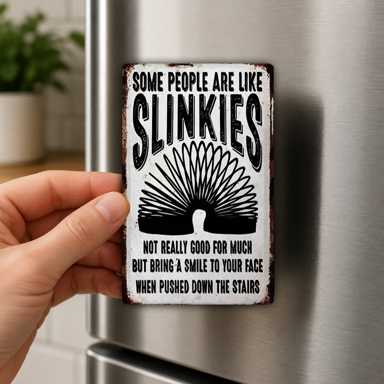 A person is holding a metal sign with a humorous message about slinking people.