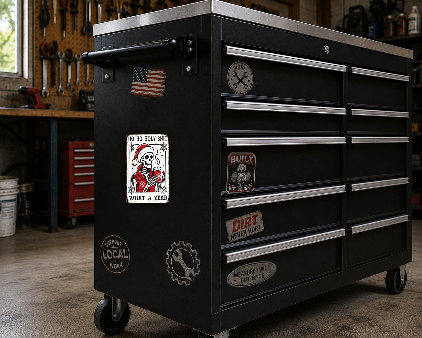 A black workbench with various stickers and labels on it, including a skeleton wearing a Santa hat and the text "What a year".