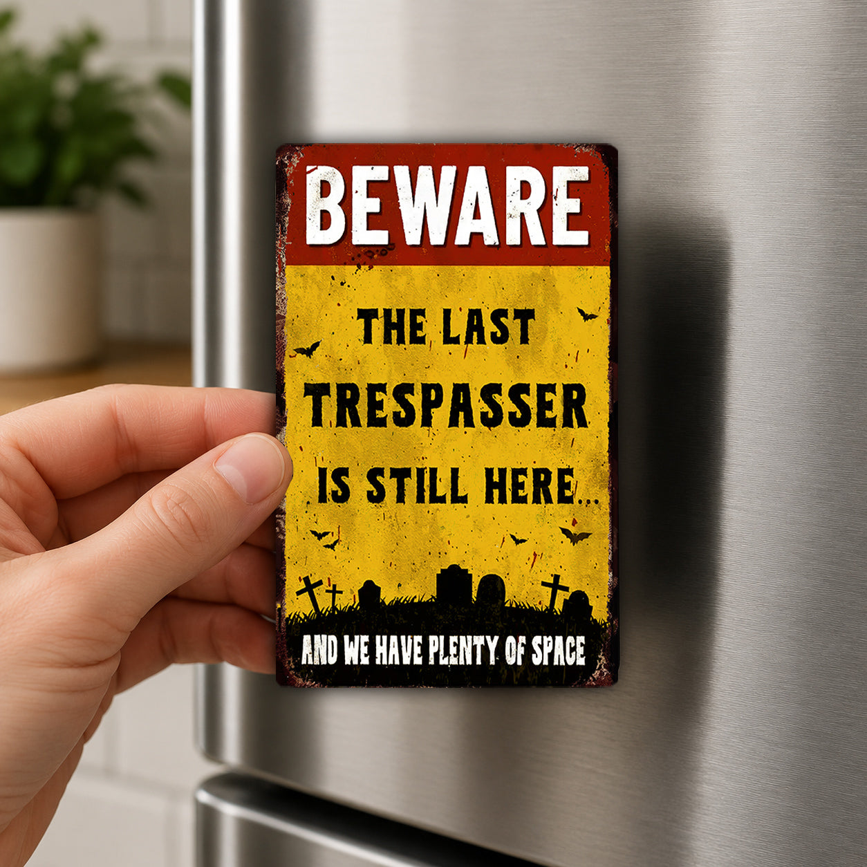 A person's hand is holding a metal refrigerator magnet with a warning sign on it.