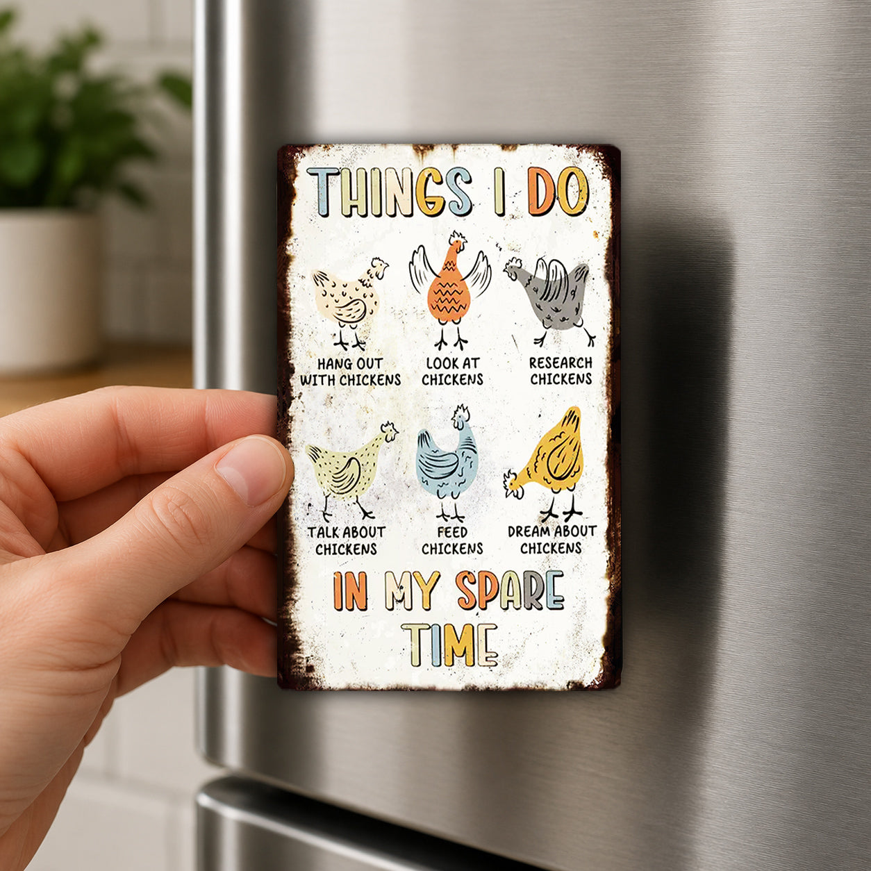 a person holding a small, colorful metal sign with illustrations of chickens and text that says "THINGS I DO IN MY SPARE TIME".