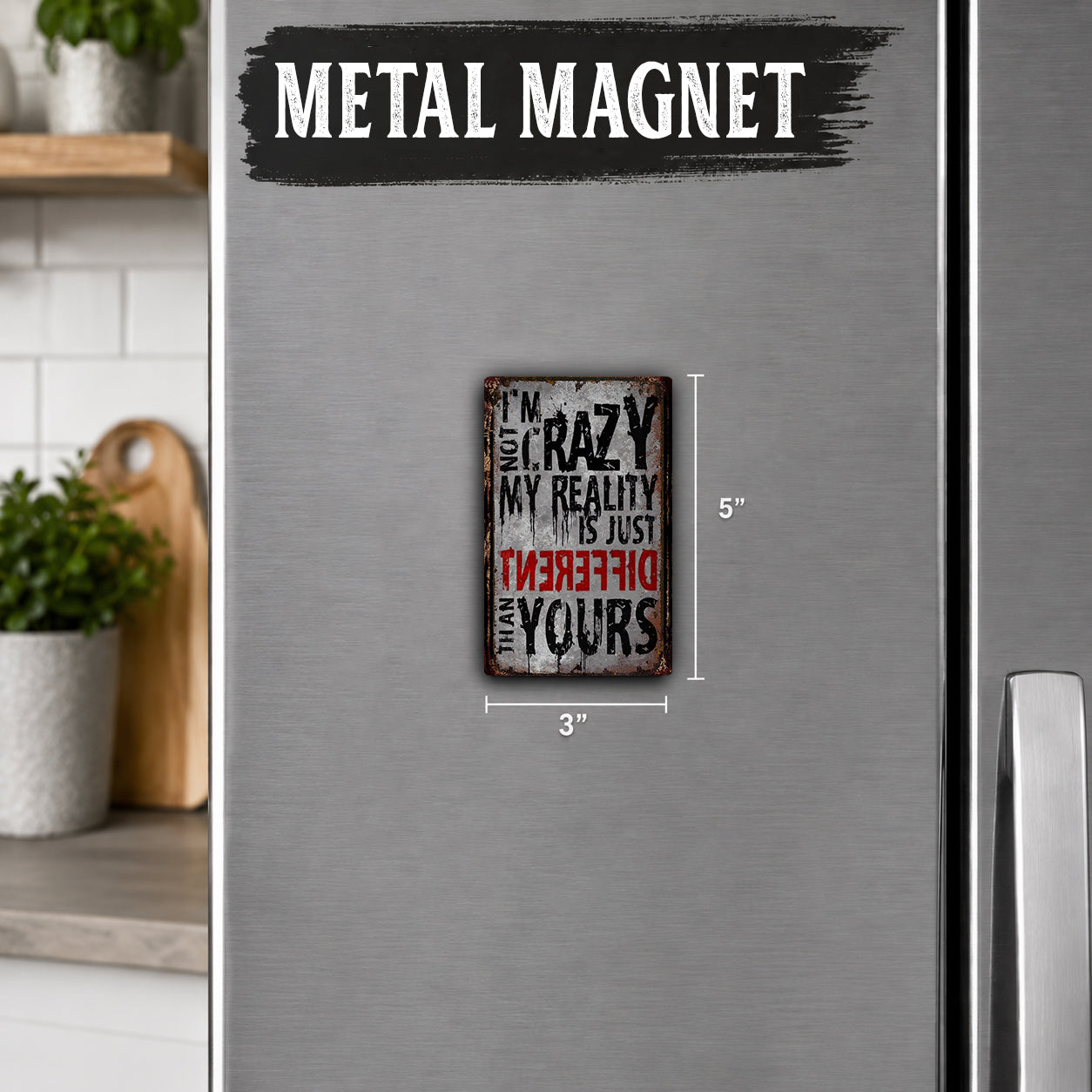 a small, metal-colored refrigerator magnet with the text "I'm crazy, my reality is just different" printed on it.