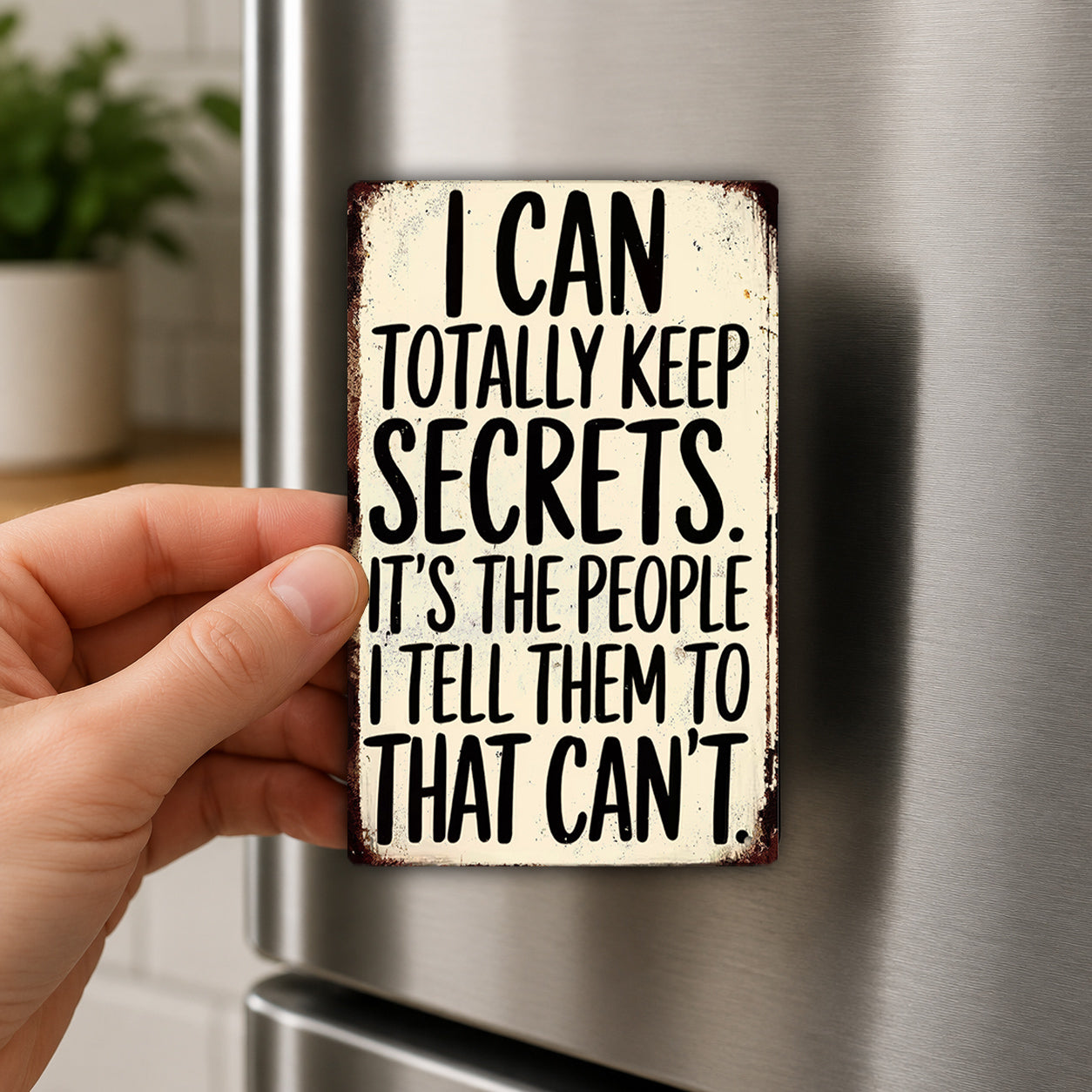 A person's hand holding a sign with the text "I CAN TOTALLY KEEP SECRETS. IT'S THE PEOPLE I TELL THEM TO THAT CAN'T" on it.