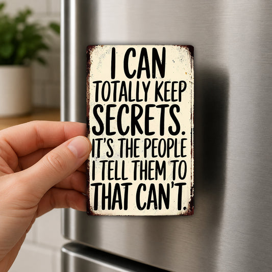 A person's hand holding a sign with the text "I CAN TOTALLY KEEP SECRETS. IT'S THE PEOPLE I TELL THEM TO THAT CAN'T" on it.