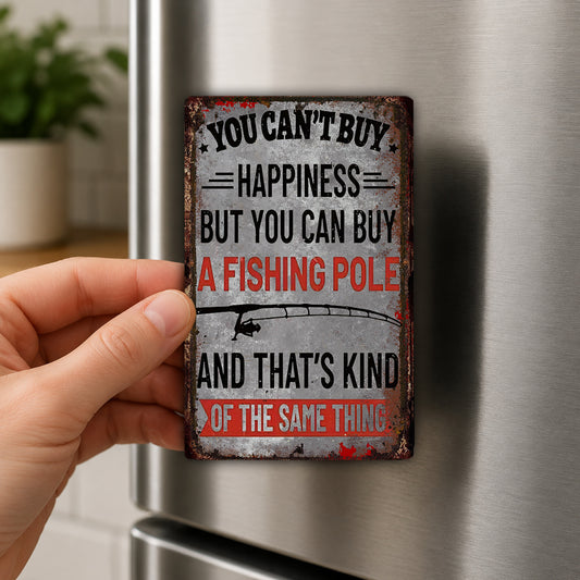 A person's hand is holding a rusty, vintage-style magnet with a humorous message about happiness and fishing poles.