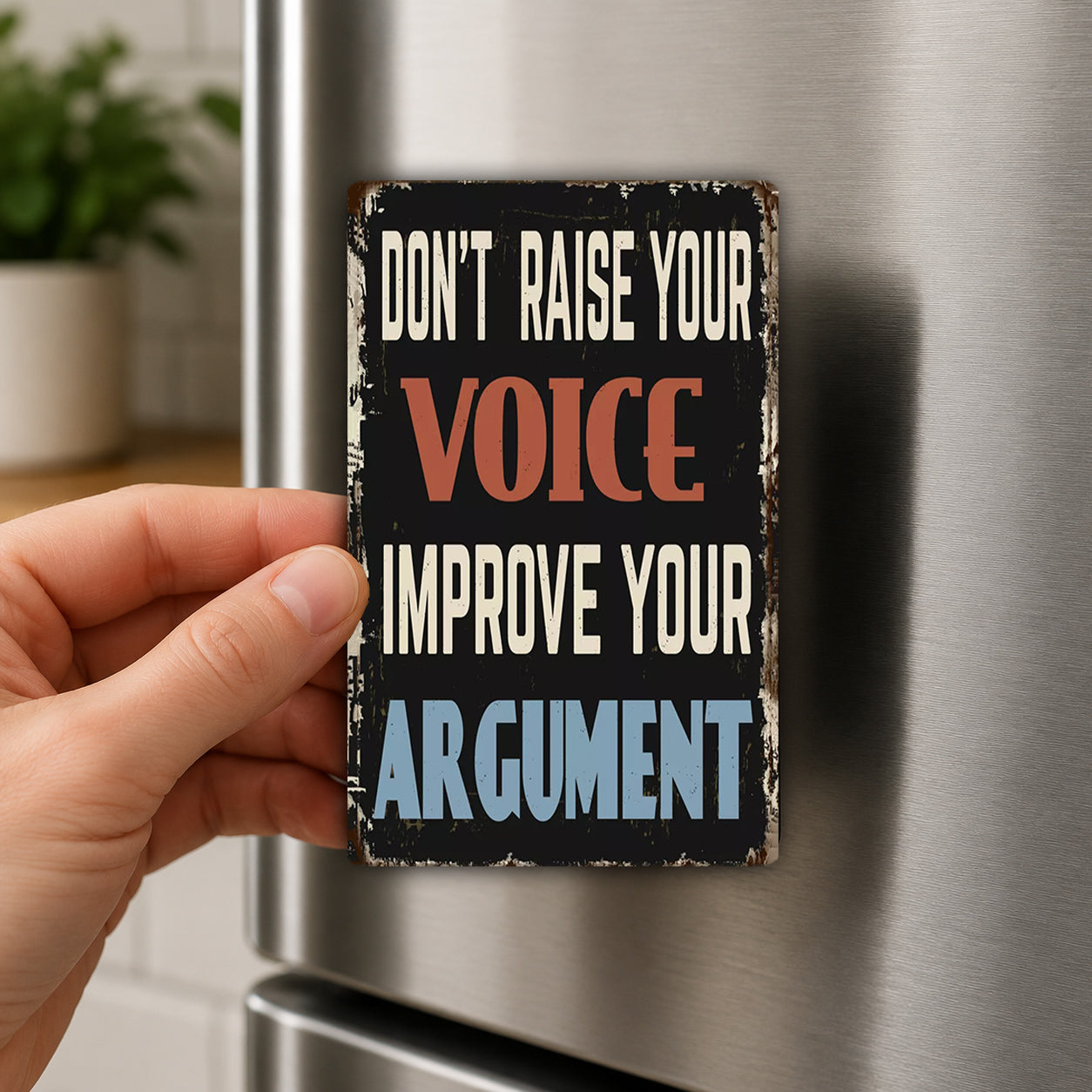 A person's hand holding a sign with the text "Don't raise your voice, improve your argument" on it.
