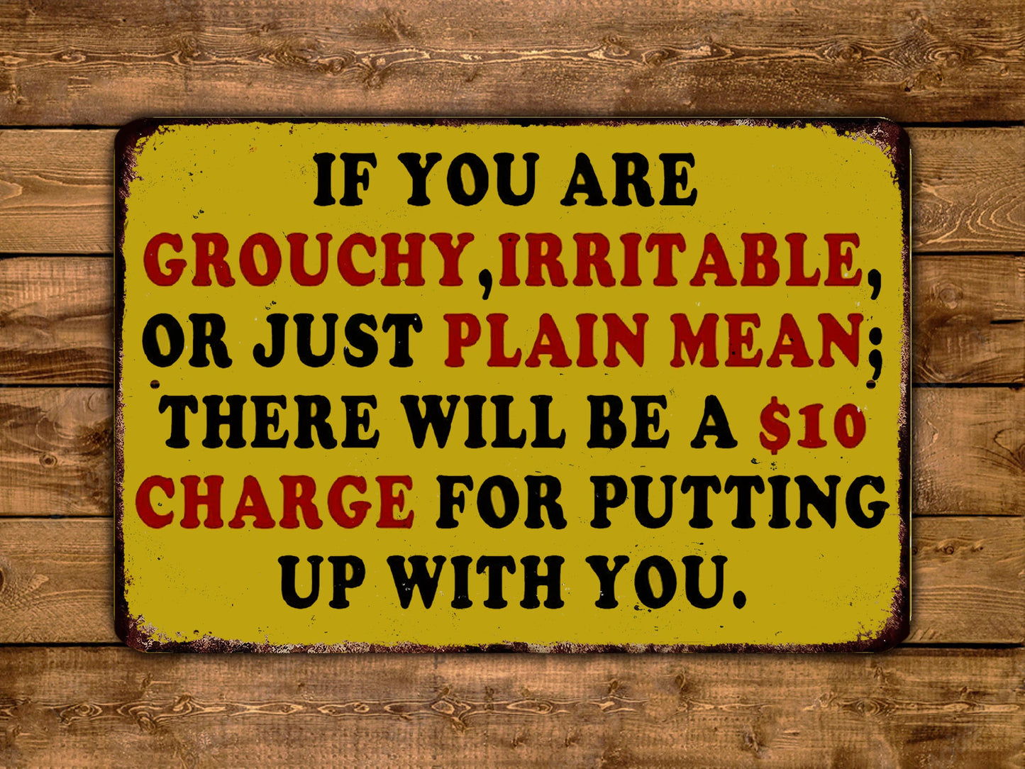 The image is a yellow sign with black text that reads "IF YOU ARE GROUCHY, IRRITABLE, OR JUST PLAIN MEAN; THERE WILL BE A $10 CHARGE FOR PUTTING UP WITH YOU."