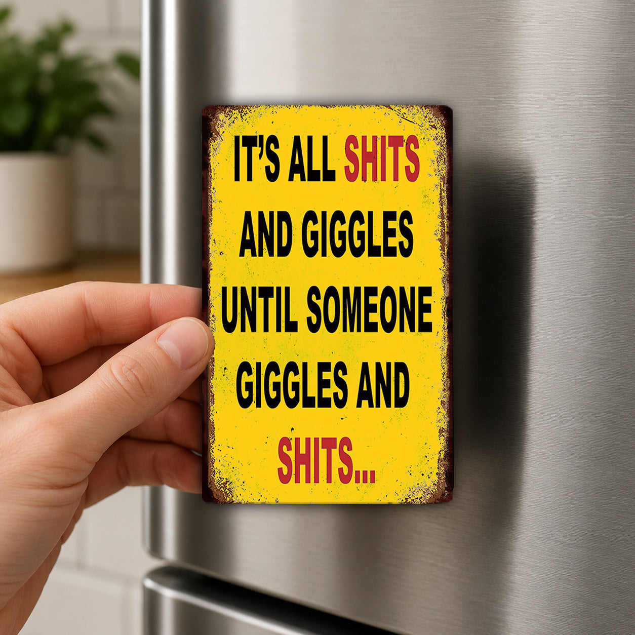A person's hand is holding a yellow sign with the text "IT'S ALL SHITS AND GIGGLES UNTIL SOMEONE GIGGLES AND SHITS..."
