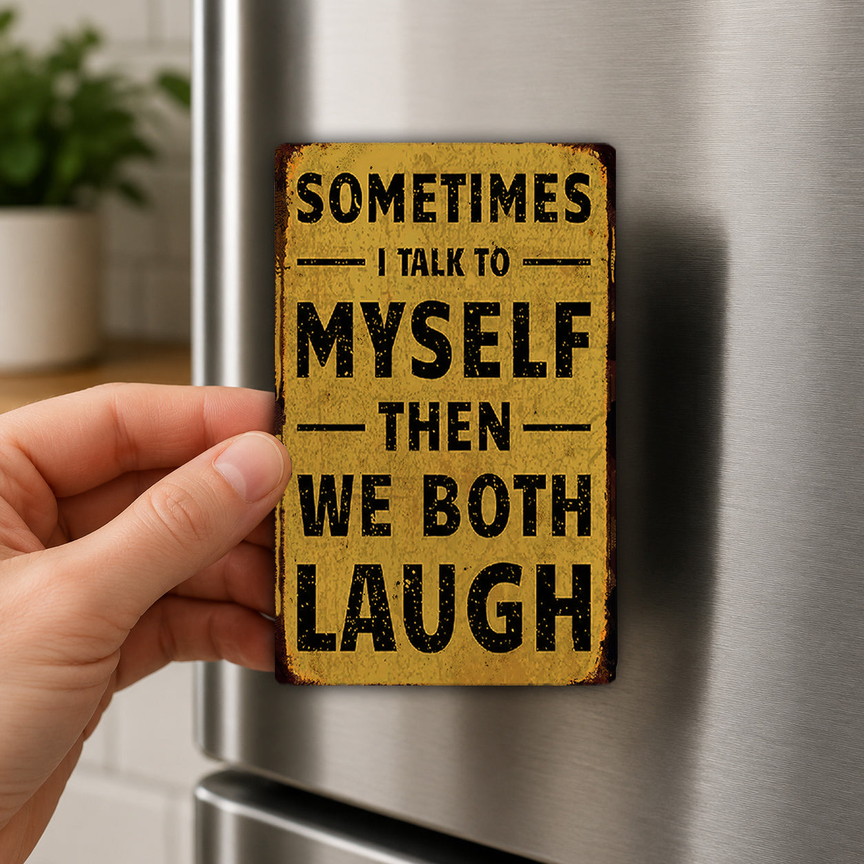 A hand holding a small, yellow sign with the text "Sometimes I talk to myself then we both laugh" on it.