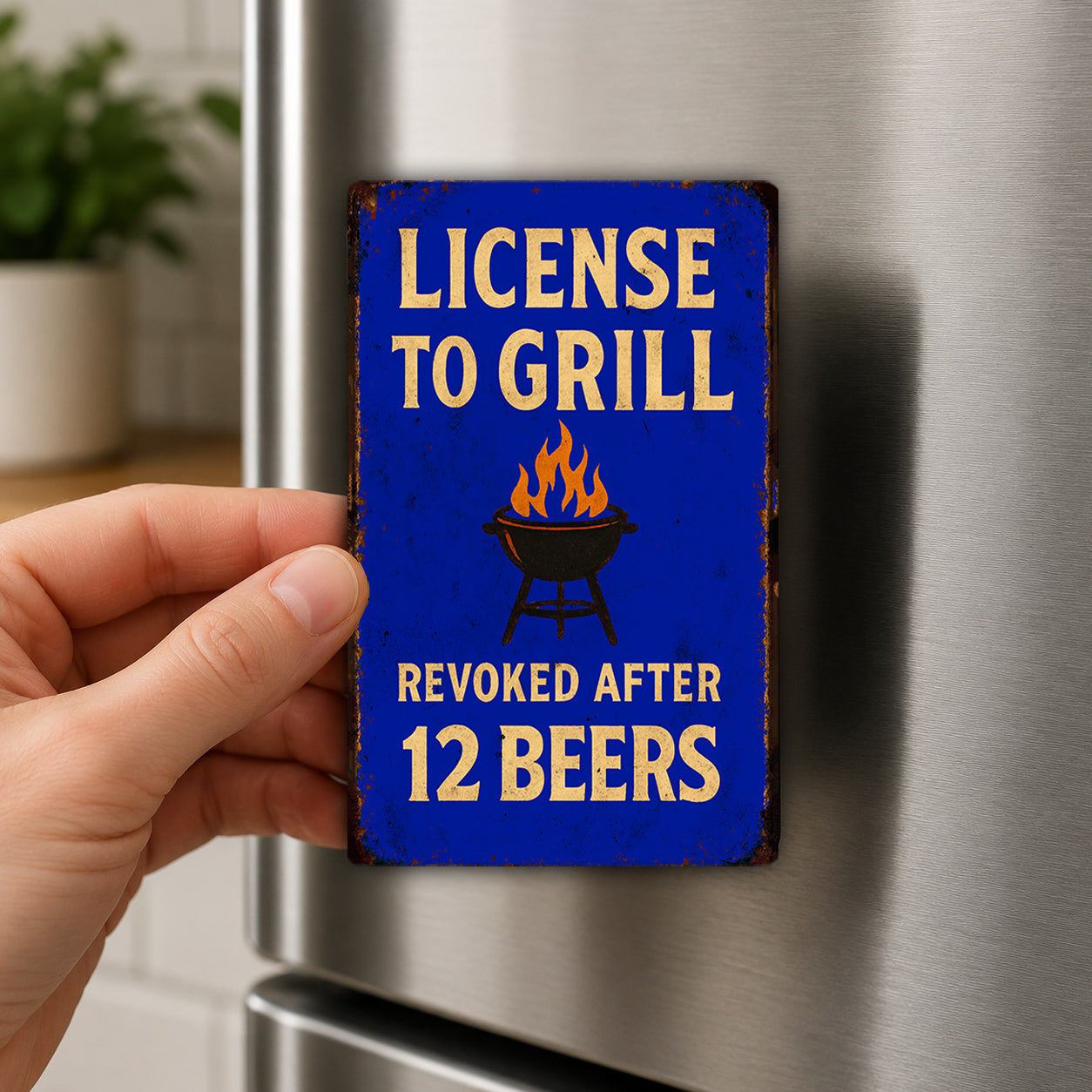 A person's hand is holding a blue sign with the text "LICENSE TO GRILL" and "REVOKE AFTER 12 BEERS" on it.