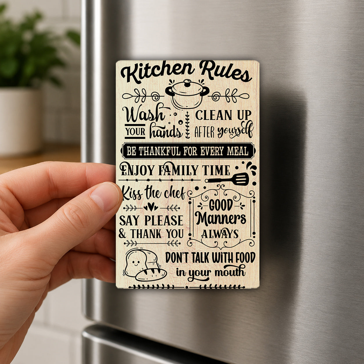 A hand holding a wooden sign with various kitchen rules and etiquette guidelines written on it.