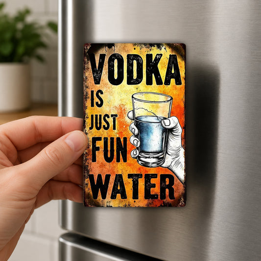 A hand is holding a metal magnet with the text "VODKA IS JUST FUN WATER" and an illustration of a glass of water.