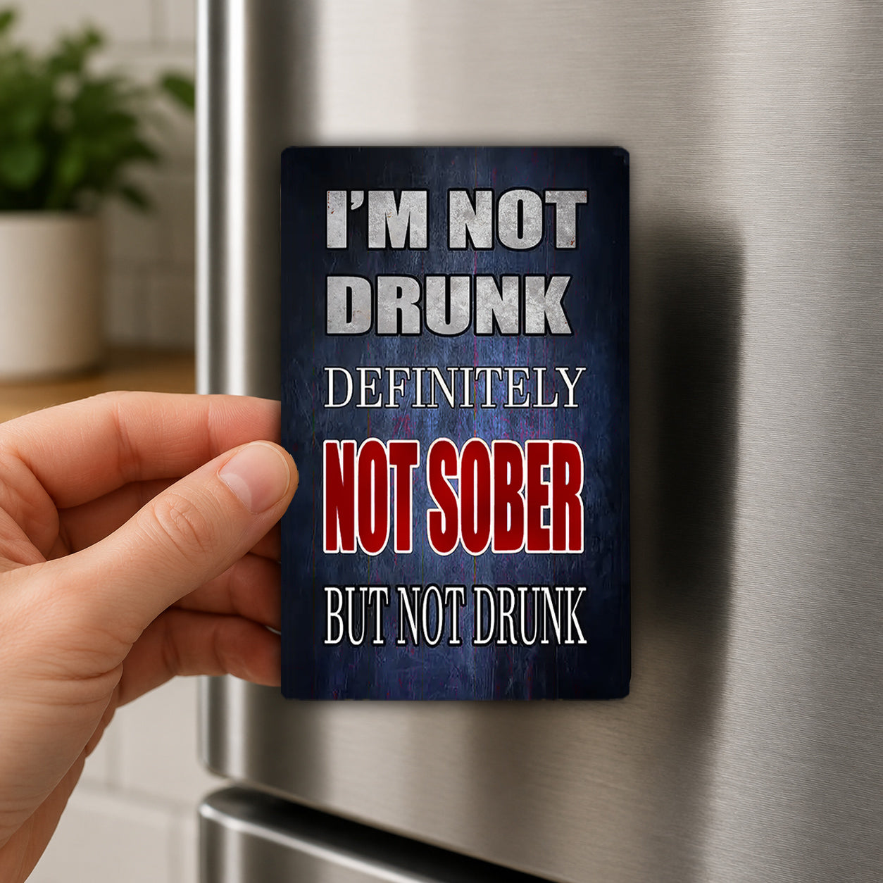 A person's hand is holding a magnet with the text "I'M NOT DRUNK definitively NOT SOBER but not DRUNK" on it.