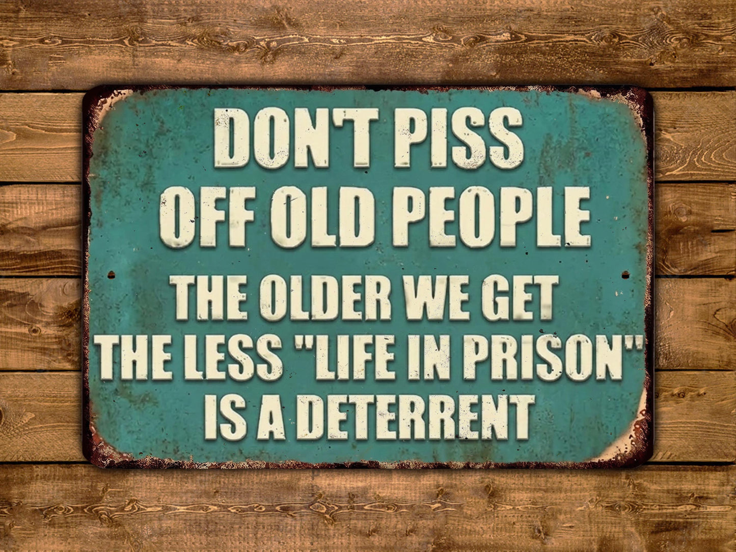 a sign with the text "DON'T PISS OFF OLD PEOPLE THE OLDER WE GET THE LESS 'LIFE IN PRISON' IS A DETERRENT" in white letters on a green background.