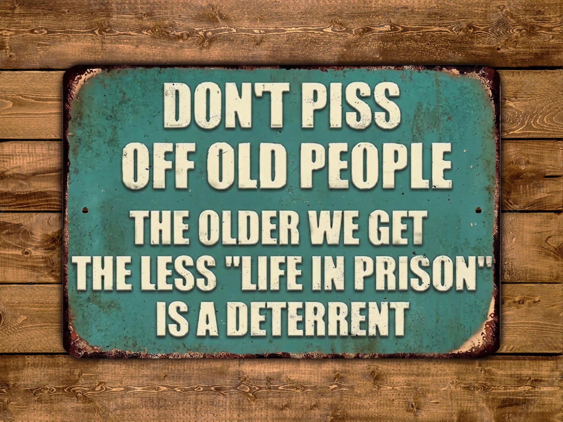 a sign with the text "DON'T PISS OFF OLD PEOPLE THE OLDER WE GET THE LESS 'LIFE IN PRISON' IS A DETERRENT" in white letters on a green background.