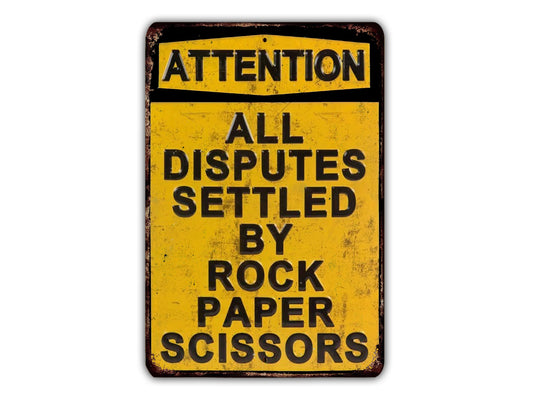 A yellow sign with black text that reads "ATTENTION ALL DISPUTES SETTLEED BY ROCK PAPER SCISSORS".