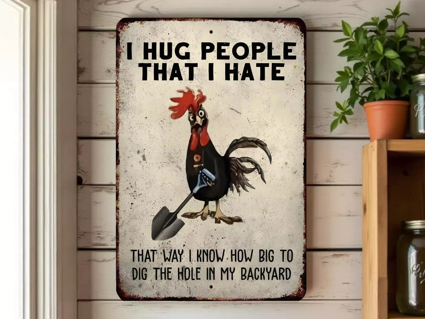 a rooster holding a shovel and standing in front of a sign that says "I HUG PEOPLE THAT I HATE".
