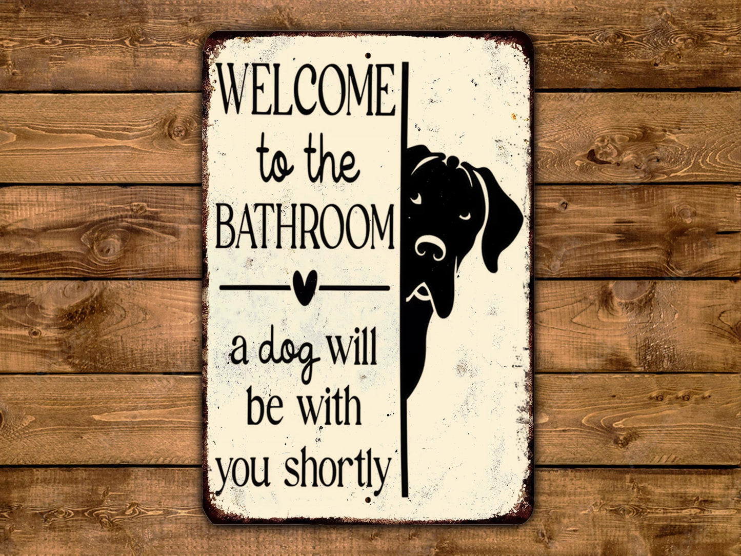 A metal sign with a black dog silhouette and text welcoming visitors to the bathroom.