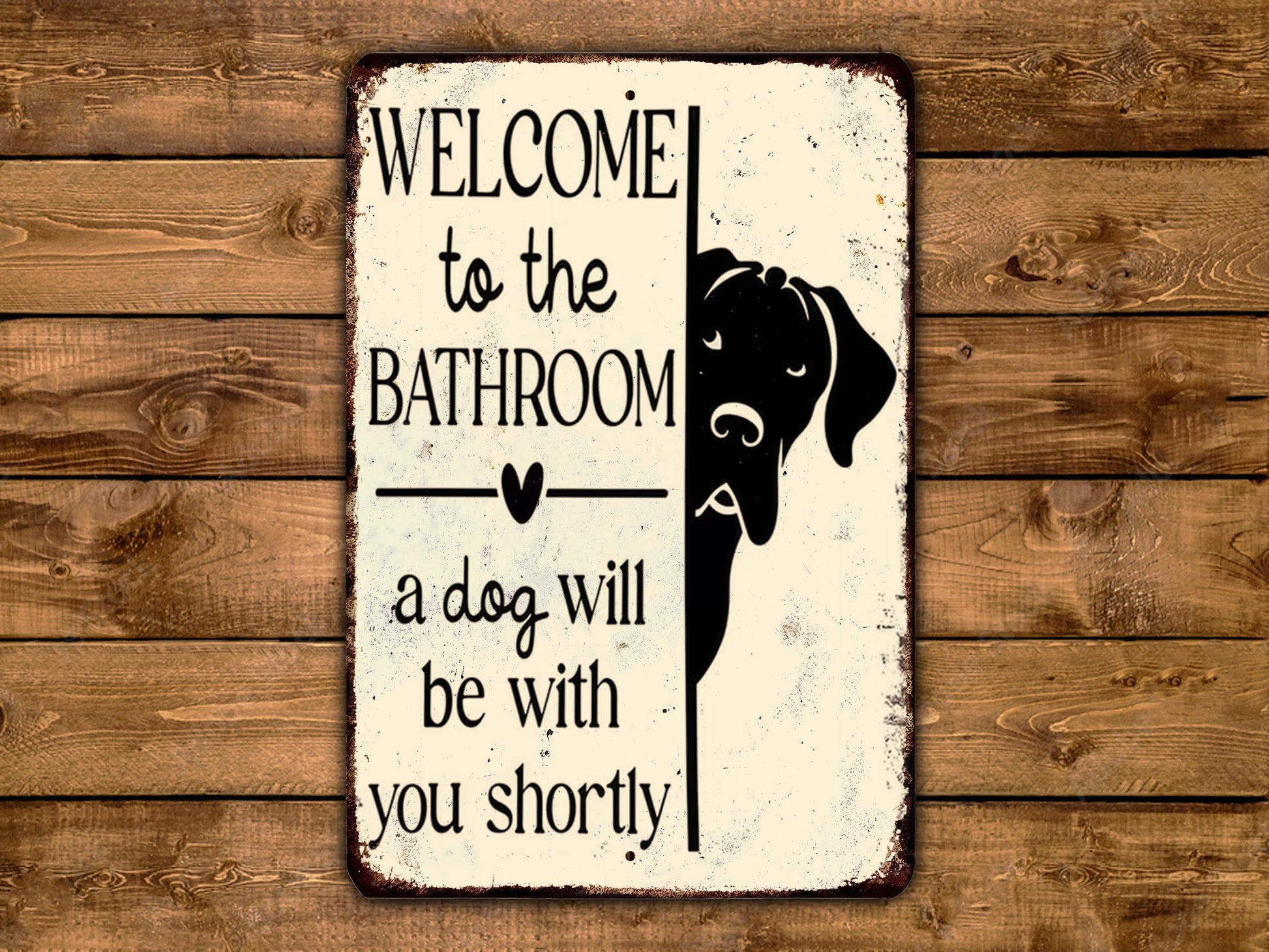 A metal sign with a black dog silhouette and text welcoming visitors to the bathroom.