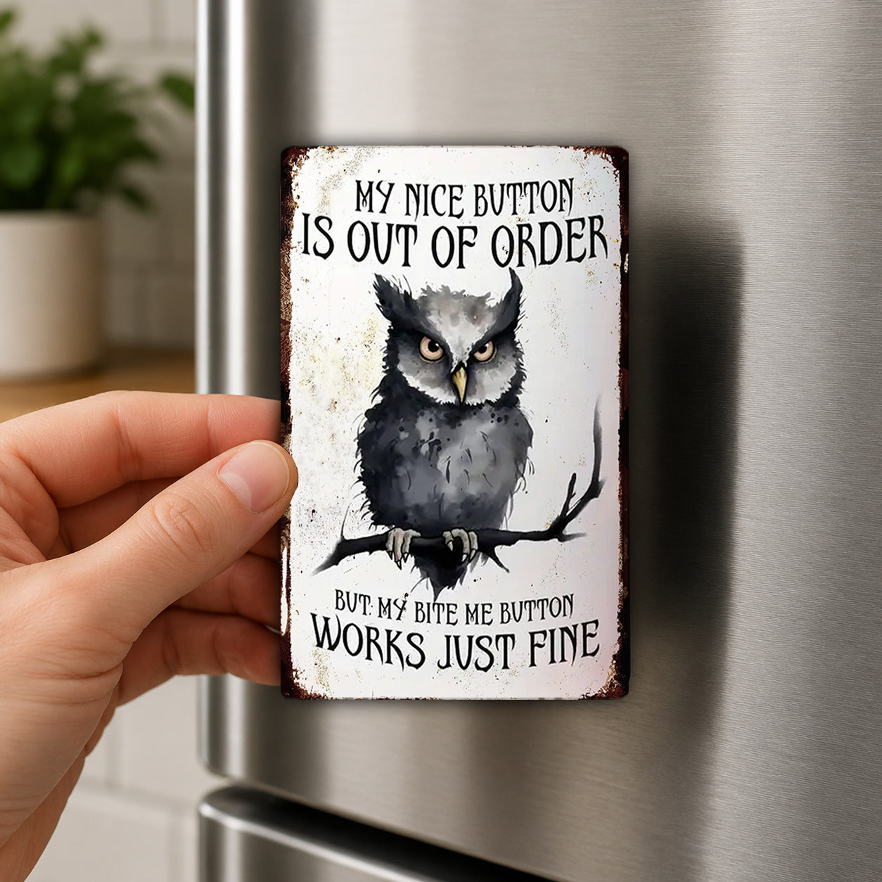 A person's hand holding a metal sign with an owl on it, which appears to be a humorous or playful message.