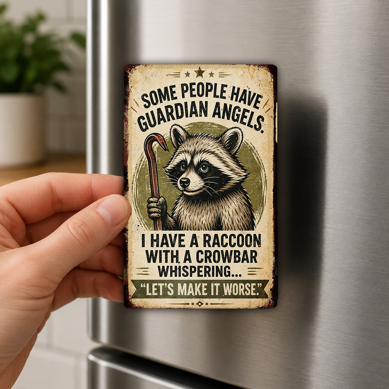 A person's hand is holding a metal refrigerator magnet with a raccoon illustration and text.