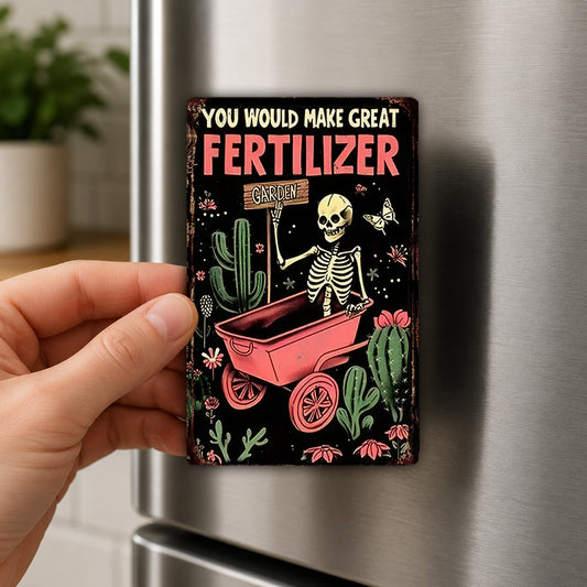 A person's hand is holding a small, colorful magnet with a skeleton and a cactus on it, which appears to be a humorous or whimsical design.