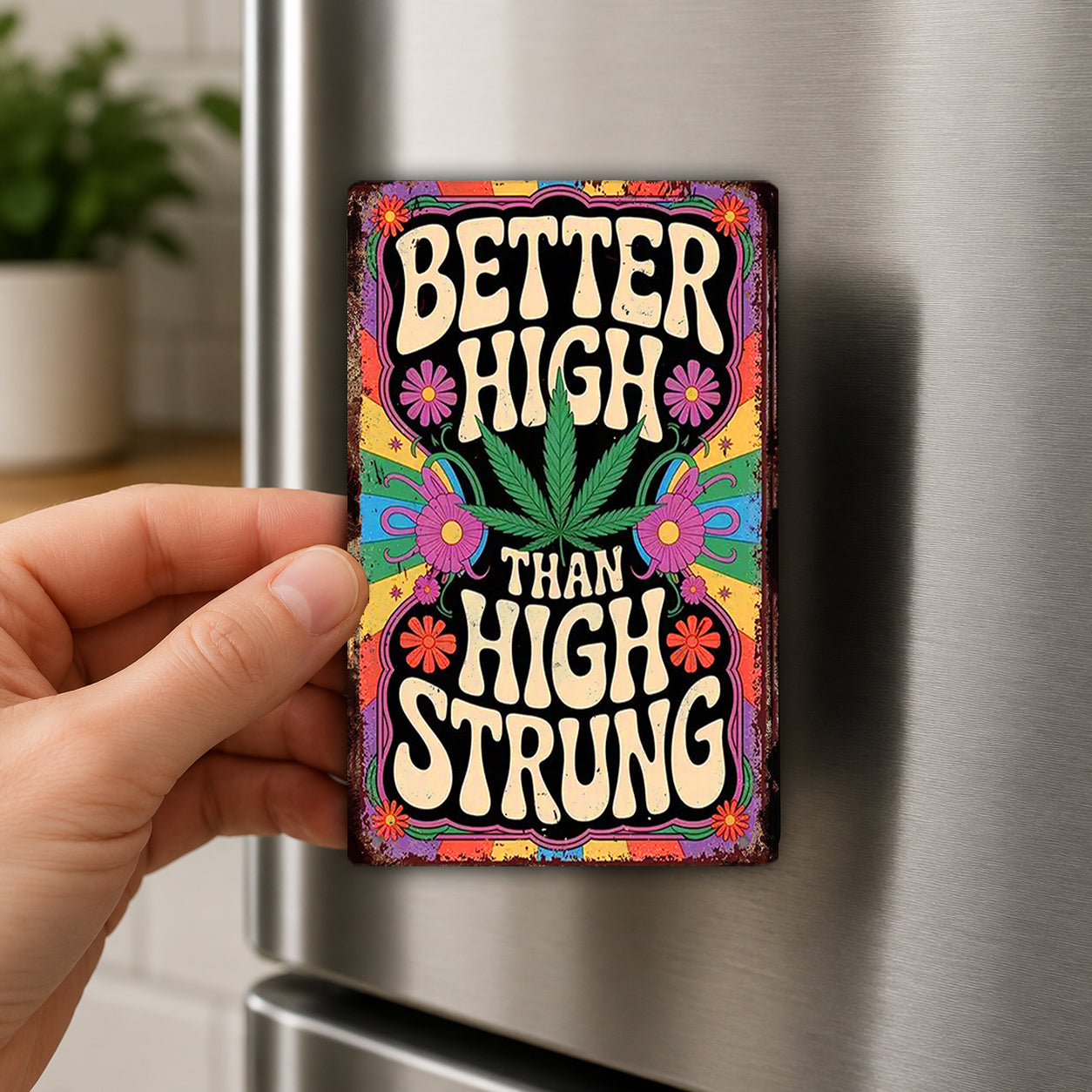 A hand holding a colorful, vintage-style magnet with the text "Better High Than High Strung" on it.