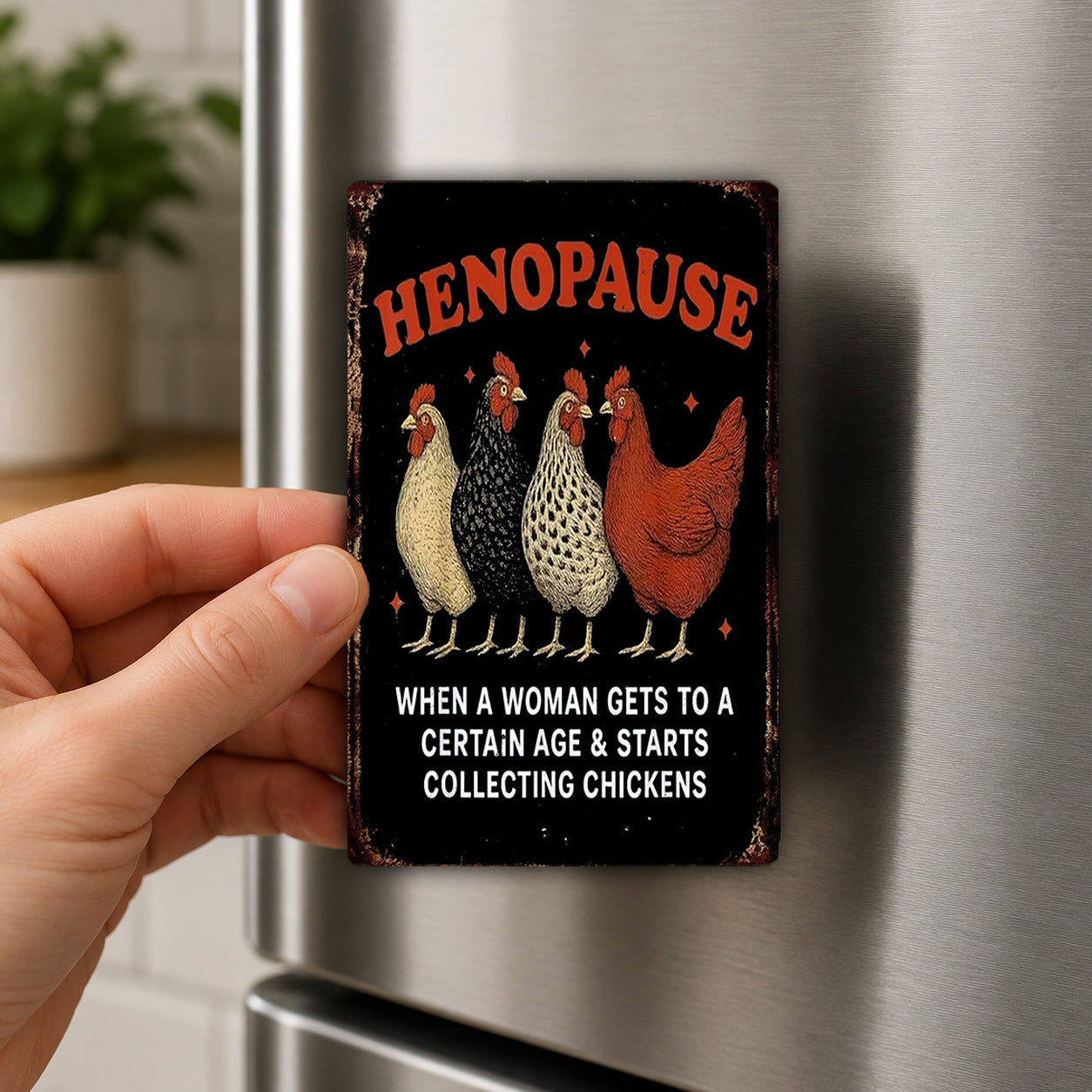 A person's hand is holding a refrigerator magnet with a humorous text and illustrations of four chickens.