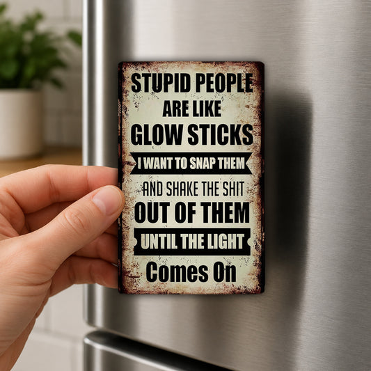 a person's hand holding a metal sign with a humorous and abrasive message about stupid people.
