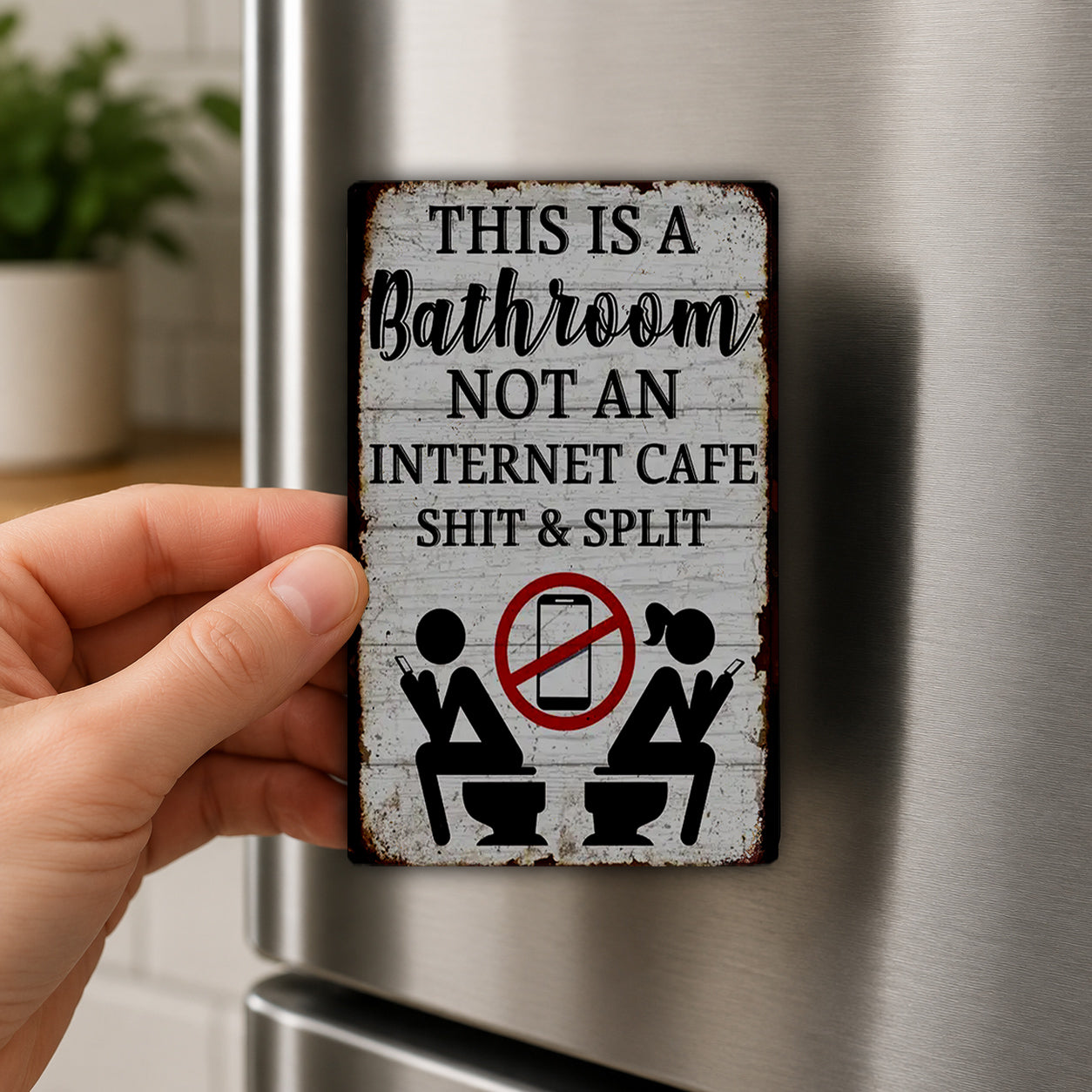 a person's hand holding a metal sign with a humorous message about a bathroom not being an internet cafe.