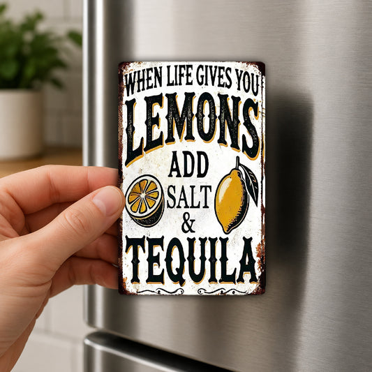A person's hand is holding a metal sign with the text "WHEN LIFE GIVES YOU LEMONS ADD SALT & TEQUILA" on it.