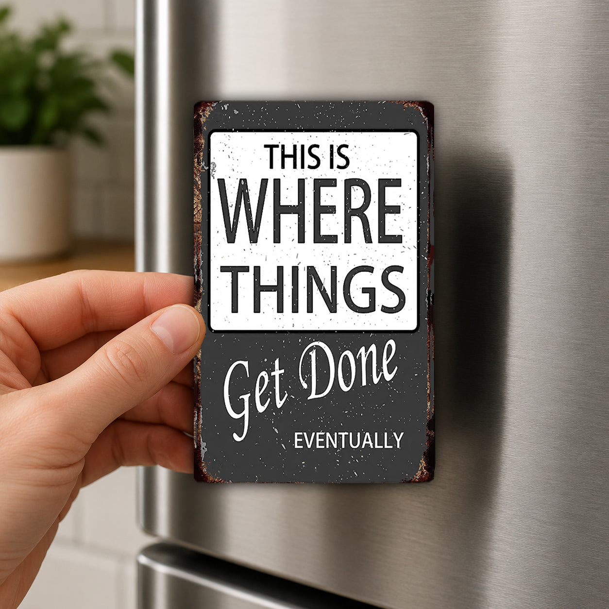 A hand is holding a black and white sign with the text "THIS IS WHERE THINGS GET DONE" and "EVENTUALLY" on it.