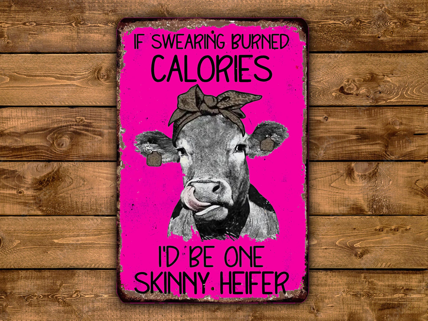 The image is a humorous sign featuring a cow with a bow on its head, accompanied by the text "If burning calories, I'd be one skinny. Heifer".