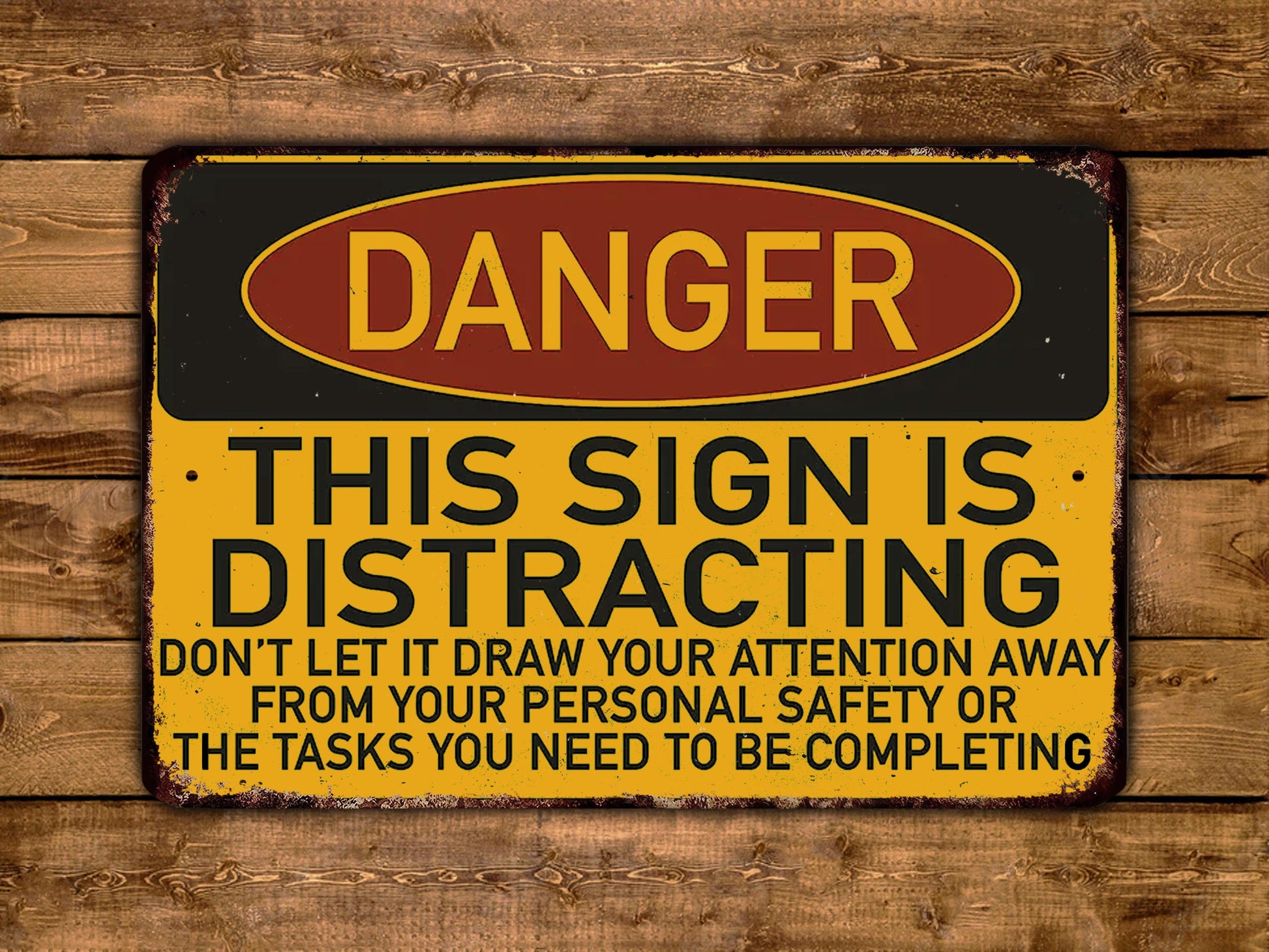 The image is a warning sign with the word "DANGER" in bold letters, indicating a potential hazard or danger. The sign also contains a cautionary message that says "THIS SIGN IS DISTRACTING" and advises not to draw attention away from personal safety or the tasks that need to be completed.