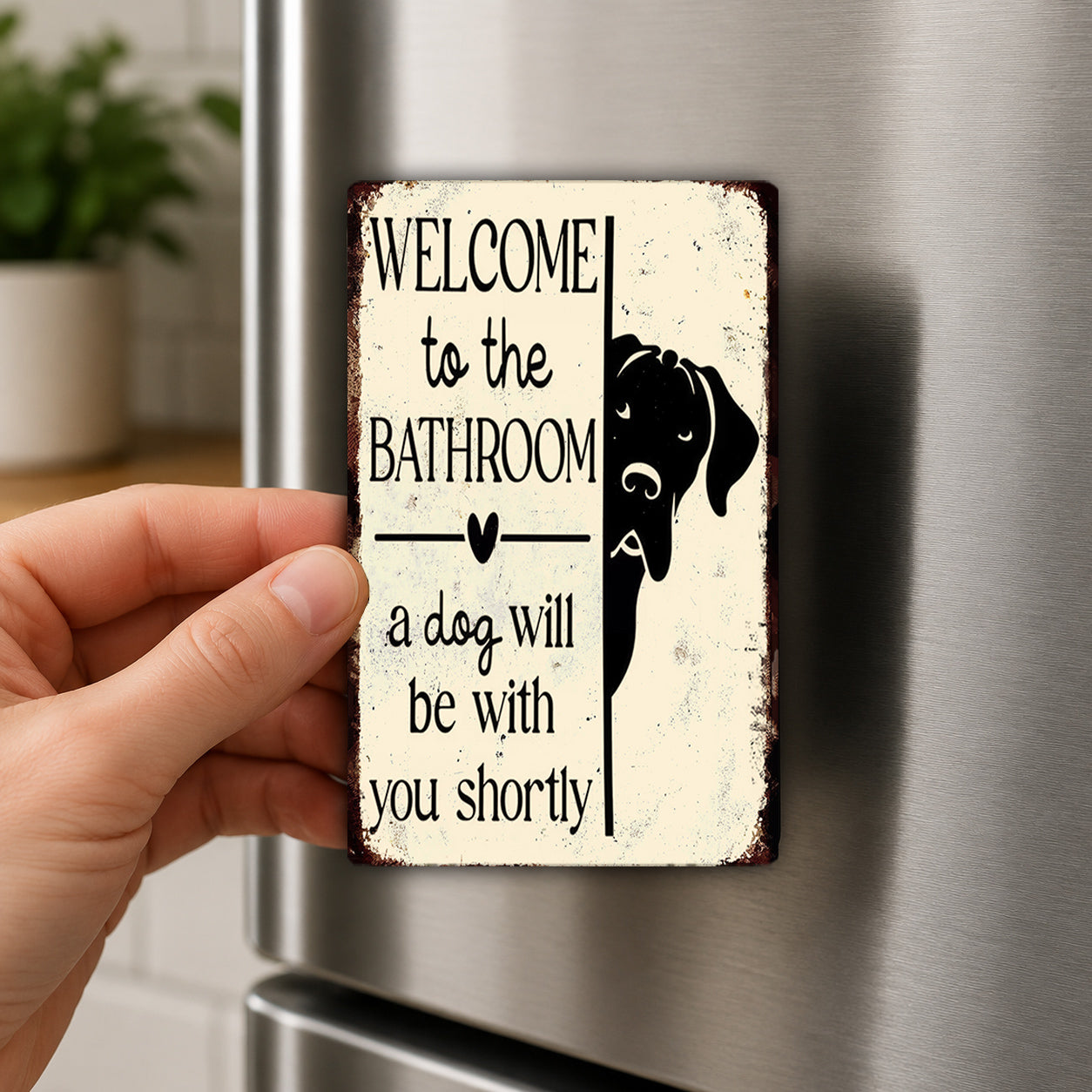 A person's hand holding a sign that says "Welcome to the Bathroom a dog will be with you shortly".
