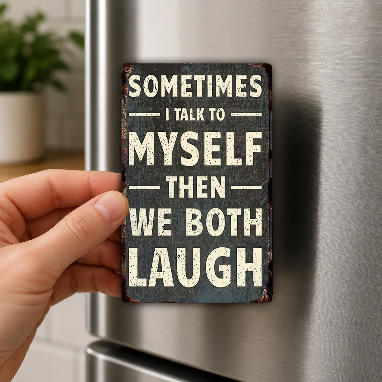 a person's hand holding a small metal sign with the text "Sometimes I talk to myself then we both laugh" on it.