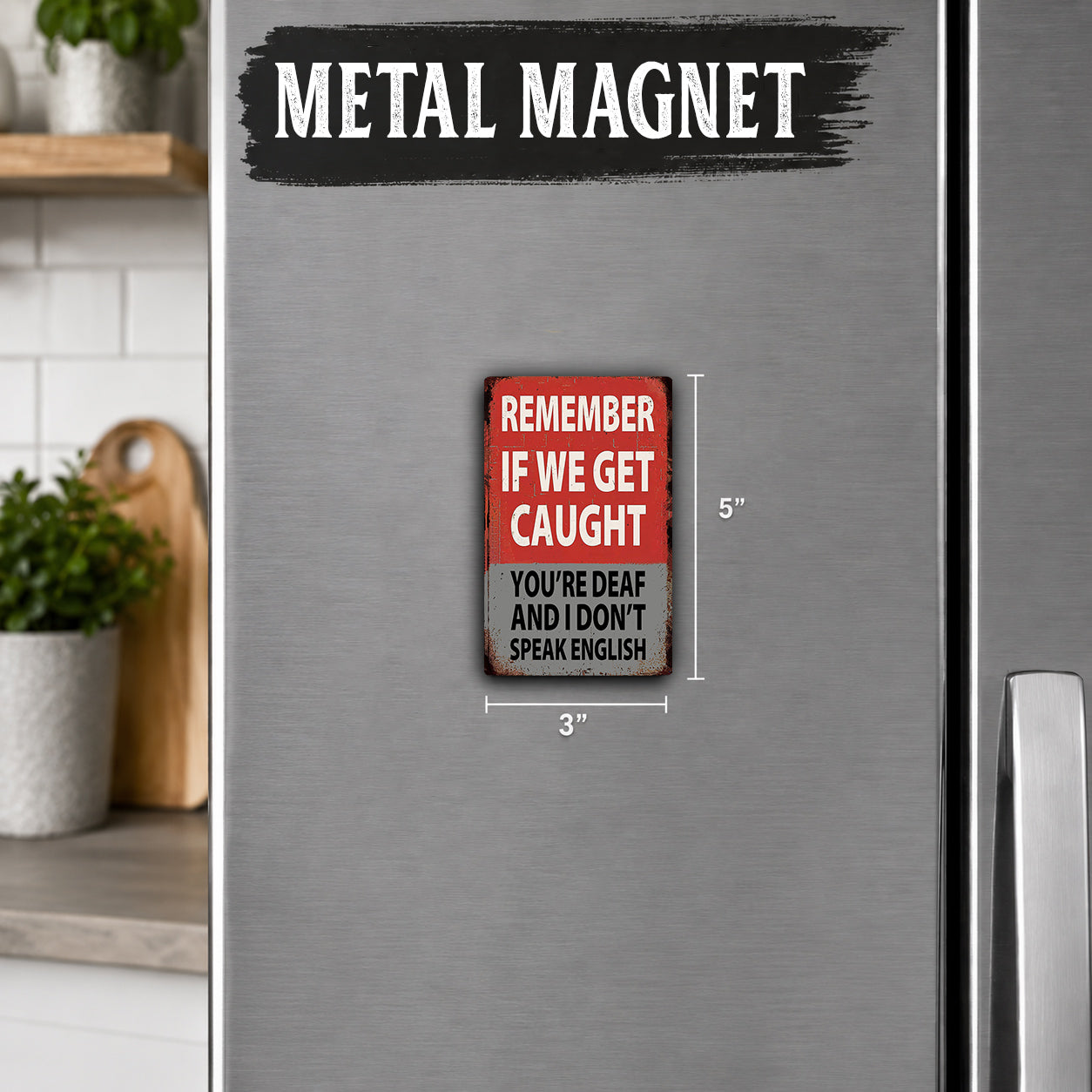 a small, red and white metal magnet on a refrigerator door. The magnet has a humorous message that reads "Remember if we get caught you're deaf and I don't speak english".