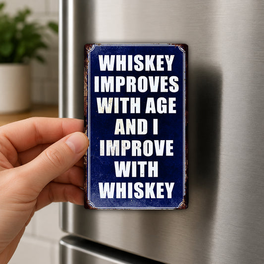 A hand is holding a blue sign with the text "WHISKEY IMPROVES WITH AGE AND I IMPROVE WITH WHISKEY" on it.