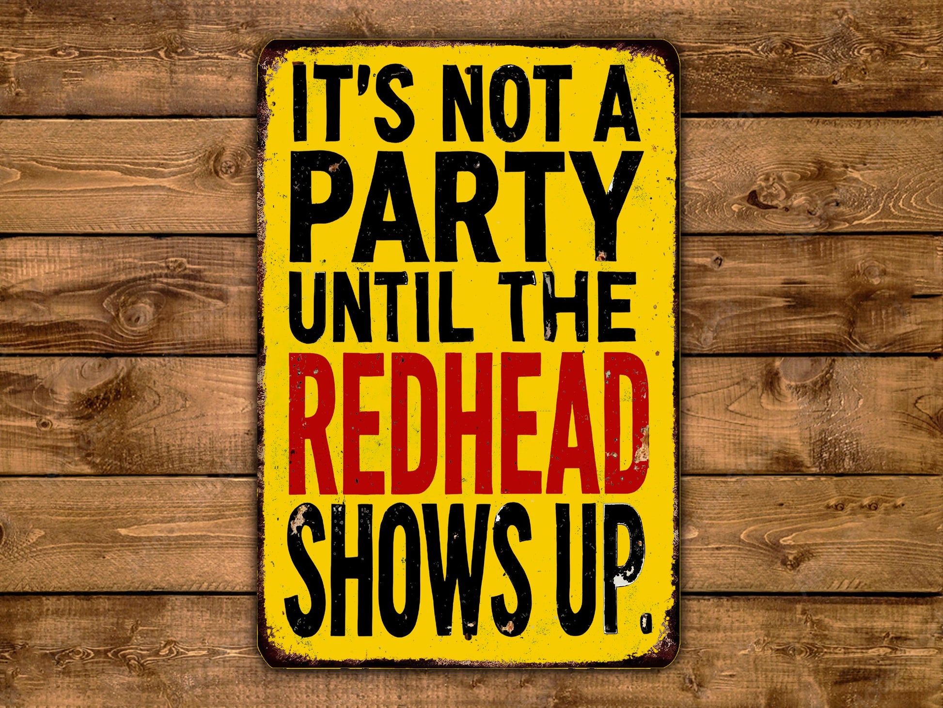 A yellow sign with black text that reads "IT'S NOT A PARTY UNTIL THE REDHEAD SHOWS UP."